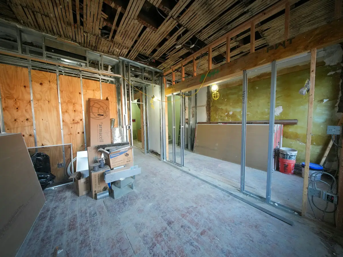 Appartement ancien mis à nu avant rénovation : cloisons ouvertes, plancher de bois, lumière de fenêtre