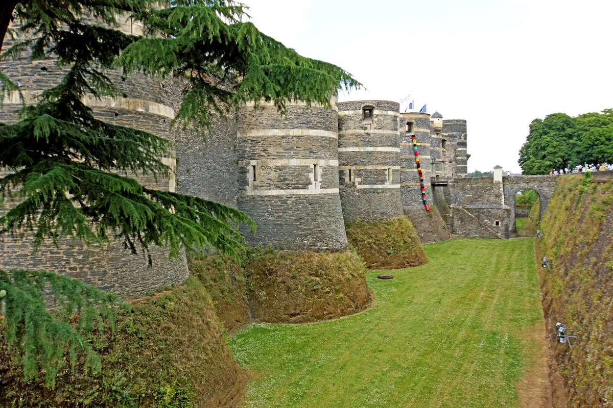 Les tours du château d’Angers, rayées d’assises de schiste sombre et de pierre claire, au-dessus des douves en jardin