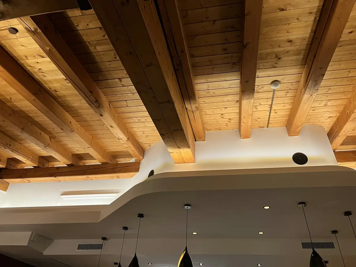 Plafond à poutres de bois apparentes, chaudes sous l’éclairage