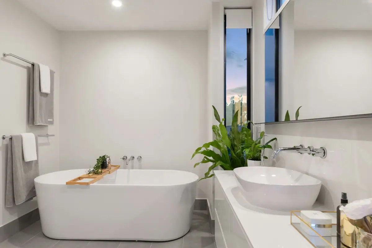 Salle de bain claire, baignoire îlot, sol en grands carreaux et vasques posées